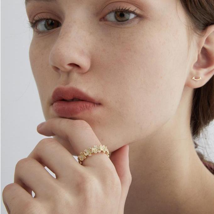 bague fleurs dorée portée par une femme avec un style élégant et minimaliste, anneau floral fin et délicat en gros plan