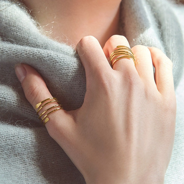 bague spirale en or vanna portée sur la main d'une femme avec un pull gris