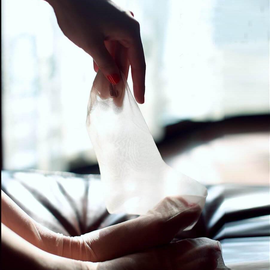 Bas femme en dentelle transparente délicatement tenu par une main élégante avec manucure rouge.