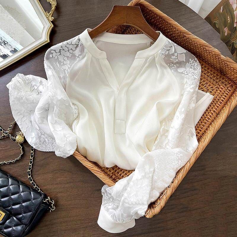 blouse fluide en dentelle blanche pour femme posée sur un cintre en bois et un panier en osier, avec un sac à main noir