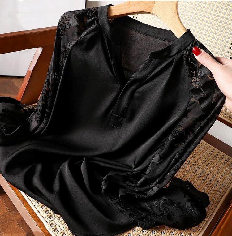 blouse fluide noire avec dentelle sur les manches, tenue sur un cintre et présentée sur une chaise en bois avec assise en cannage