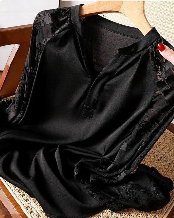 blouse fluide noire avec dentelle sur les manches, tenue sur un cintre et présentée sur une chaise en bois avec assise en cannage