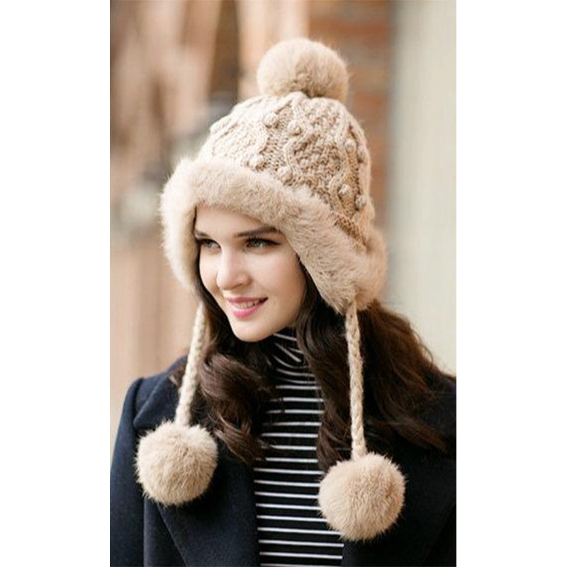 femme portant un bonnet pompon doublure polaire en laine beige avec des motifs au crochet, idéale pour l'hiver