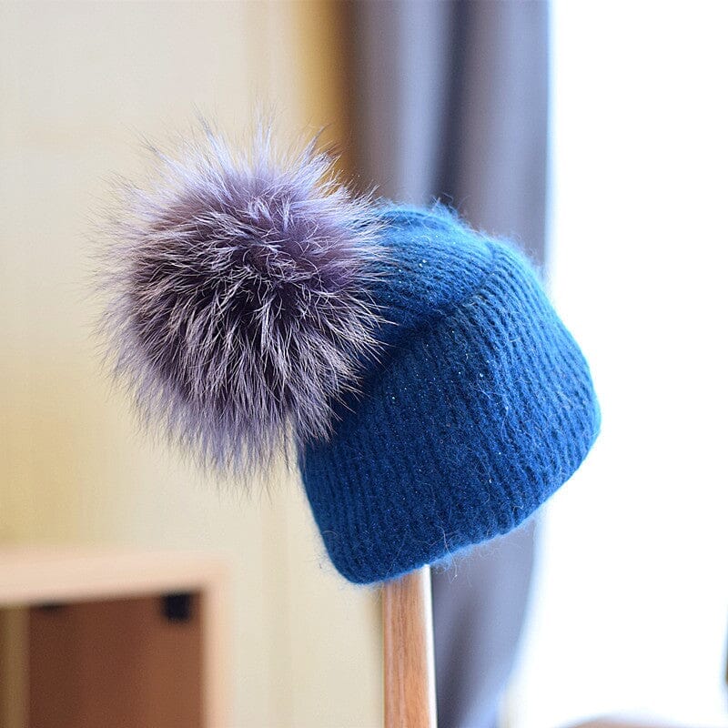 Bonnet pompon bleu pour femmes avec grosse boule de fourrure grise, idéal pour l'hiver et les journées froides.