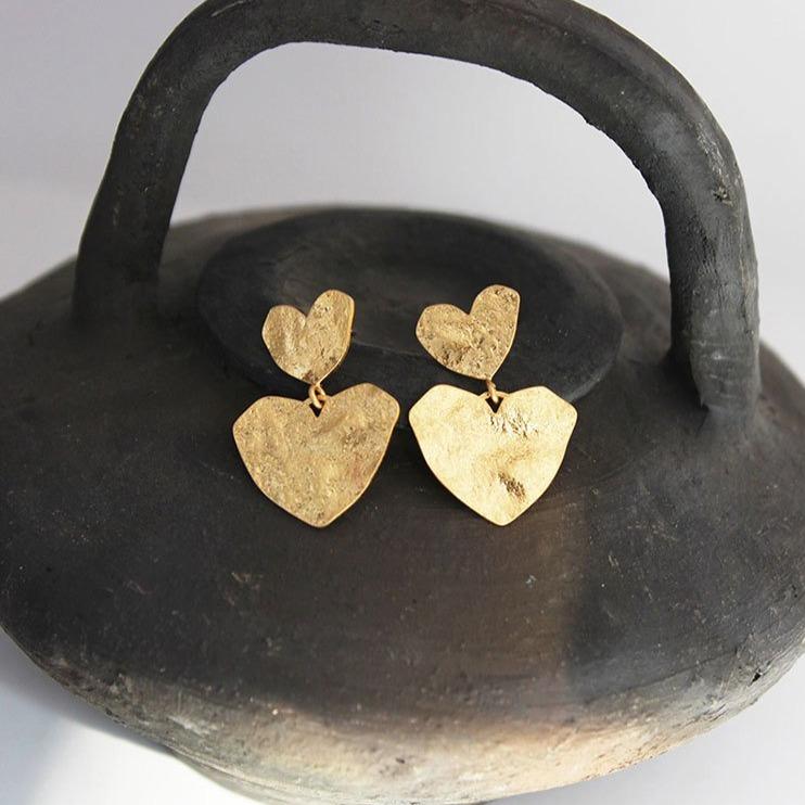 boucles d'oreilles coeur en or posées sur un support rustique, élégantes et brillantes parfaites pour toute occasion
