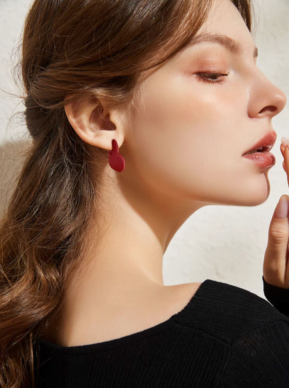 boucles d'oreilles cœur rouge élégantes portées par un modèle, ajoutent une touche glamour à toute tenue avec leur design unique
