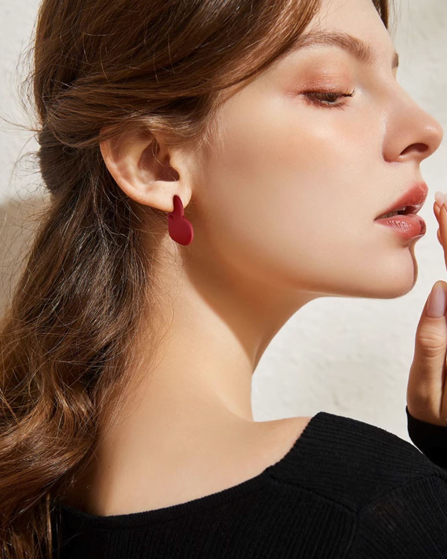 boucles d'oreilles cœur rouge élégantes portées par un modèle, ajoutent une touche glamour à toute tenue avec leur design unique