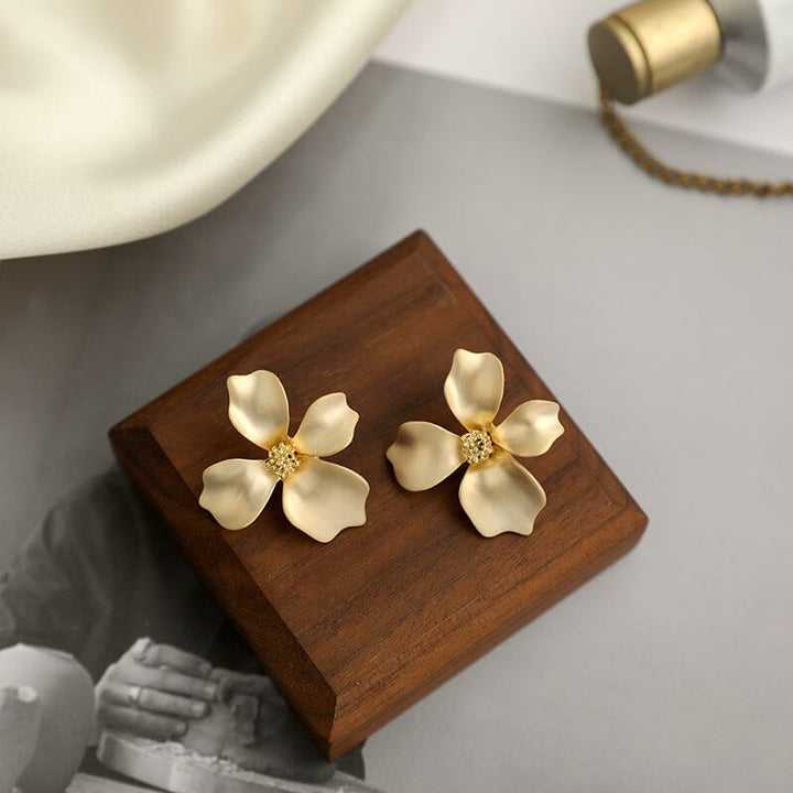 boucles d'oreilles fleurs dorées magnolia élégantes sur support en bois