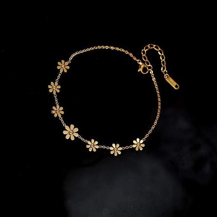 Bracelet de cheville doré orné de petites fleurs délicates, parfait pour ajouter une touche florale et élégante à votre tenue.