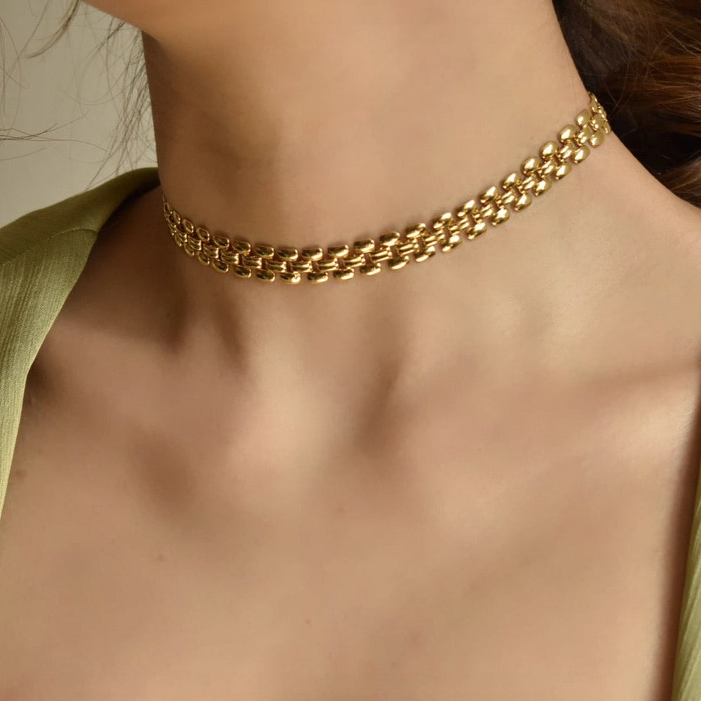 collier ras du cou doré élégant, porté par une femme, parfait pour compléter une tenue chic et moderne