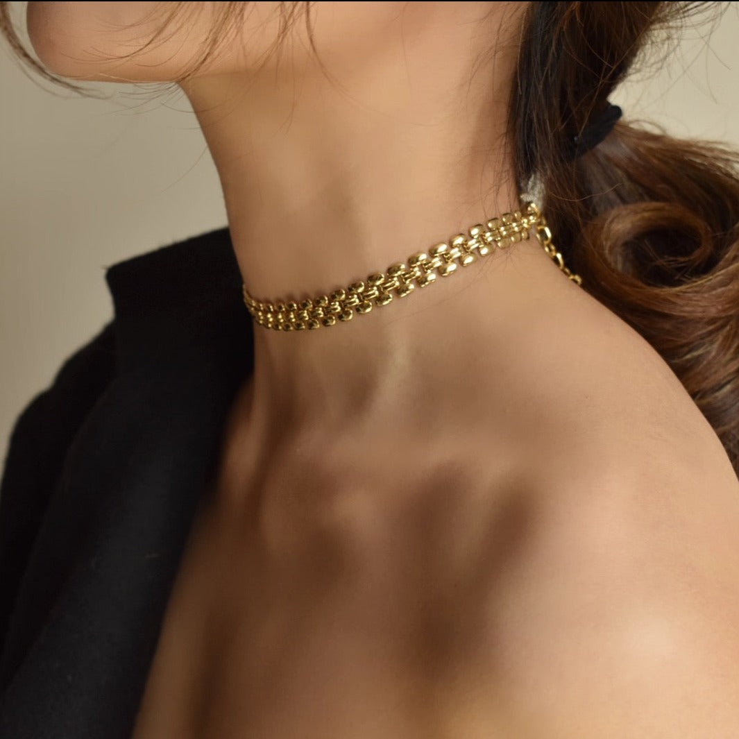 collier ras du cou élégant en métal doré porté par une femme, accessoire de mode pour un look chic et sophistiqué