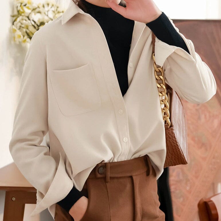 chemise hiver femme beige élégante avec poche avant portée sur pull noir, ceinture marron et sac à main chaîne dorée