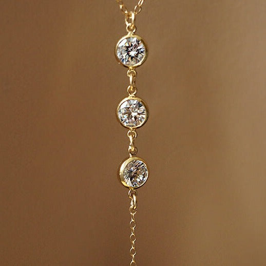 Collier de dos en or, avec trois pendentifs en diamant étincelants, parfait pour une élégance discrète et raffinée.