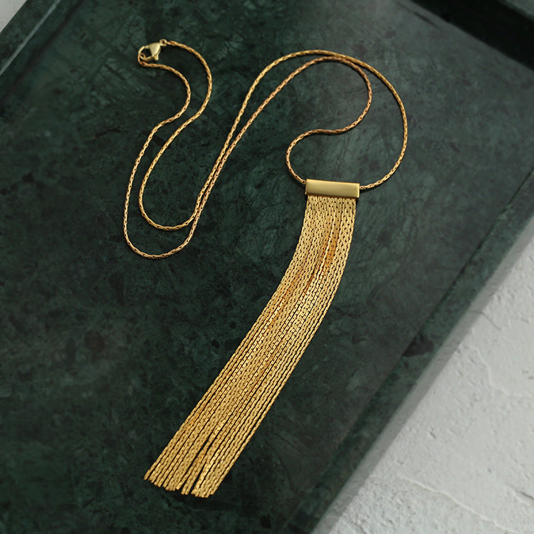 collier doré avec pendentif frange pour femme sur fond vert foncé, élégant pour des occasions spéciales ou décontractées