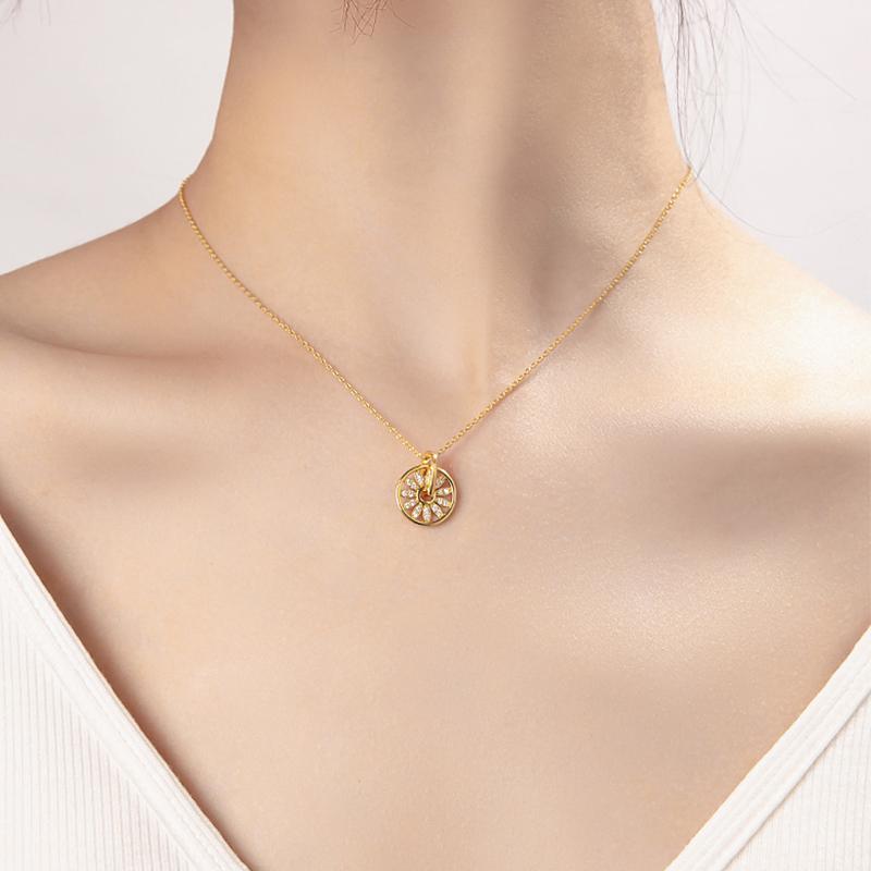 Collier pendentif rond en or avec fleur de diamants délicatement posé sur le cou d'une femme en décolleté blanc.