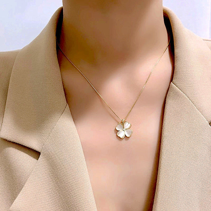 collier trèfle nacré porté par une femme, chaîne en or avec pendentif en forme de trèfle à quatre feuilles, élégance et finesse