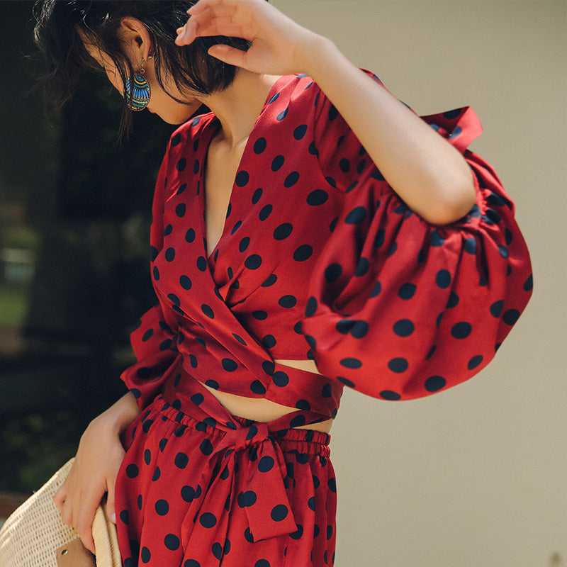 femme portant combinaison short charline rouge à pois noirs avec manches bouffantes et col en v, look estival élégant