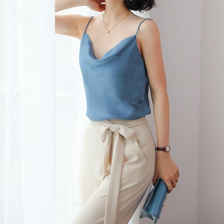 Femme portant un débardeur en satin bleu avec un pantalon beige noué à la taille et une pochette bleue.