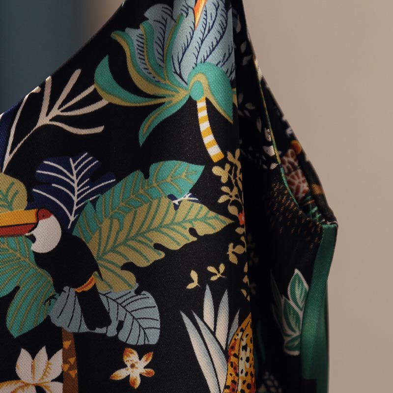 détail du tissu du débardeur tropical femme avec motifs exotiques et toucan coloré sur fond noir