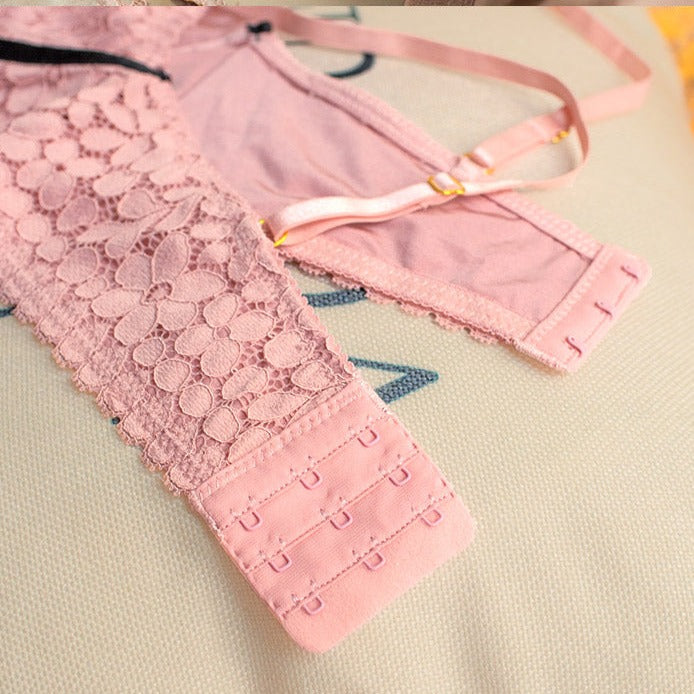 détail de l'ensemble de lingerie lola en dentelle rose avec agrafes et bretelles ajustables sur une surface beige