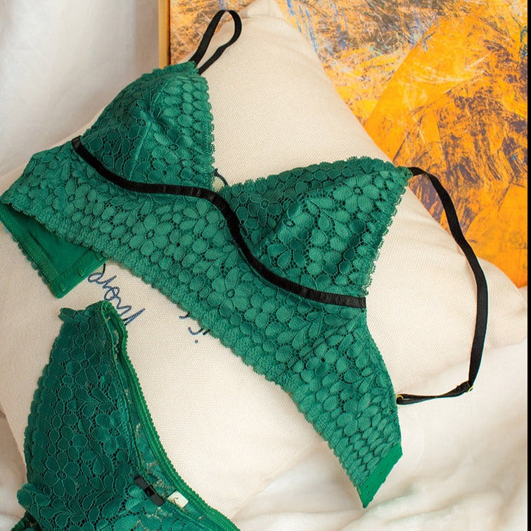 ensemble de lingerie vert en dentelle fine avec des motifs floraux et des bretelles noires posé sur un coussin