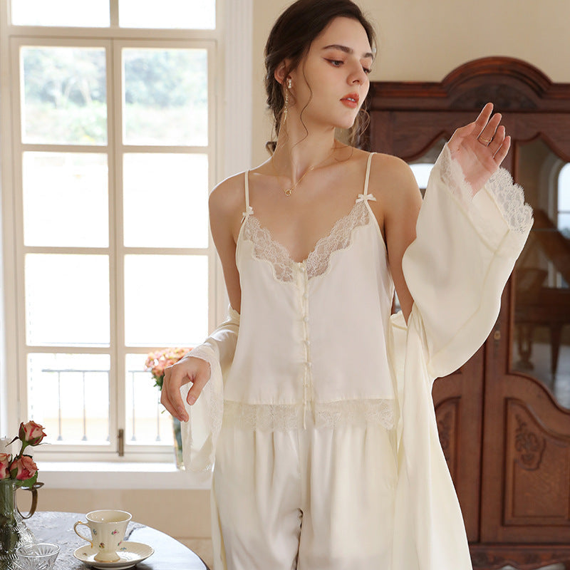 femme portant un ensemble pyjama en satin blanc cassé, composé d’un haut et d’un pantalon, dans un intérieur cozy et lumineux