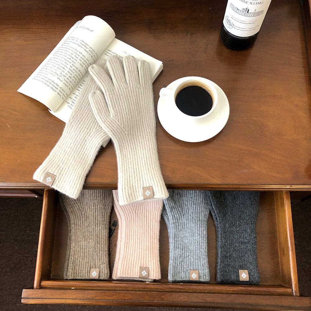 gants tactiles en laine longs posés sur une table en bois avec une tasse de café, un livre ouvert et plusieurs paires de gants dans un tiroir