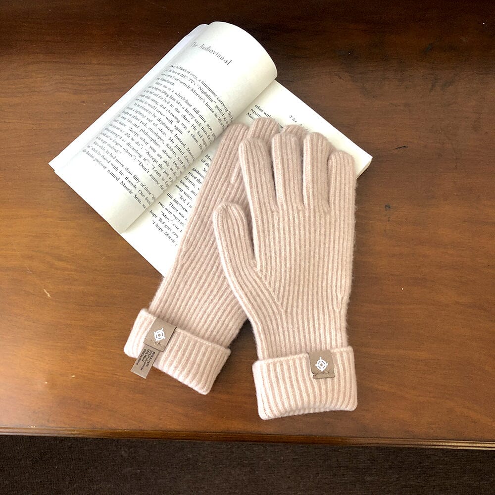 gants tactiles en laine rose posés sur un livre ouvert en bois, longs et pratiques pour l'hiver. confort et élégance