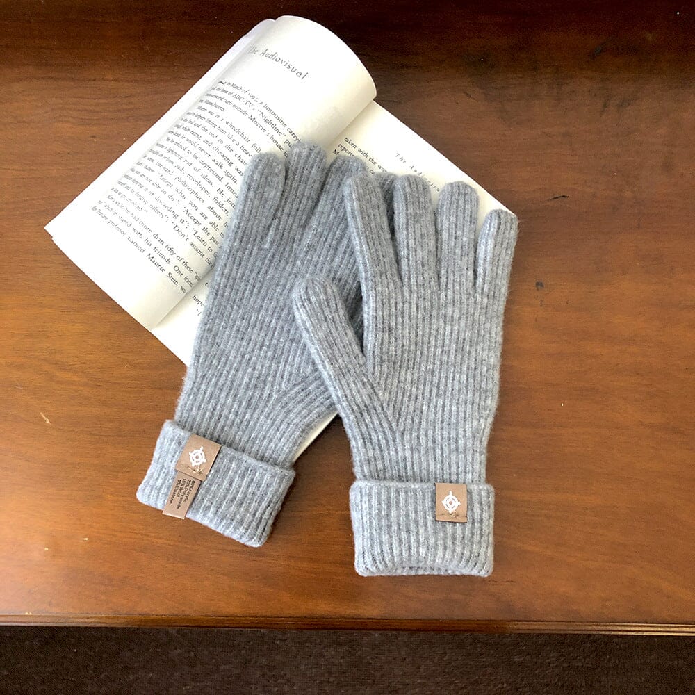 gants tactiles en laine gris longs posés sur un livre ouvert sur une table en bois