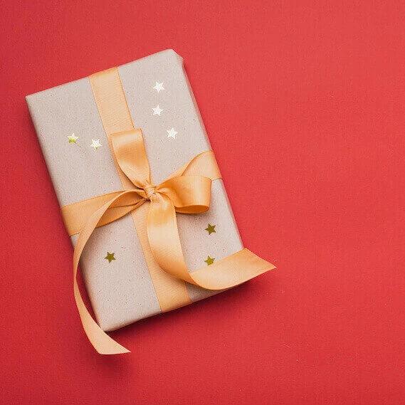 carte cadeau emballée avec un joli ruban orange sur un fond rouge, idéale pour offrir à vos proches