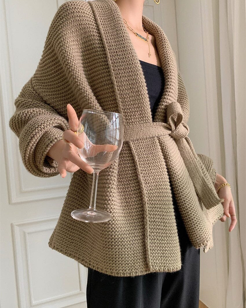 gilet sans boutons en maille beige porté par une femme tenant un verre de vin, idéal pour un look chic et décontracté