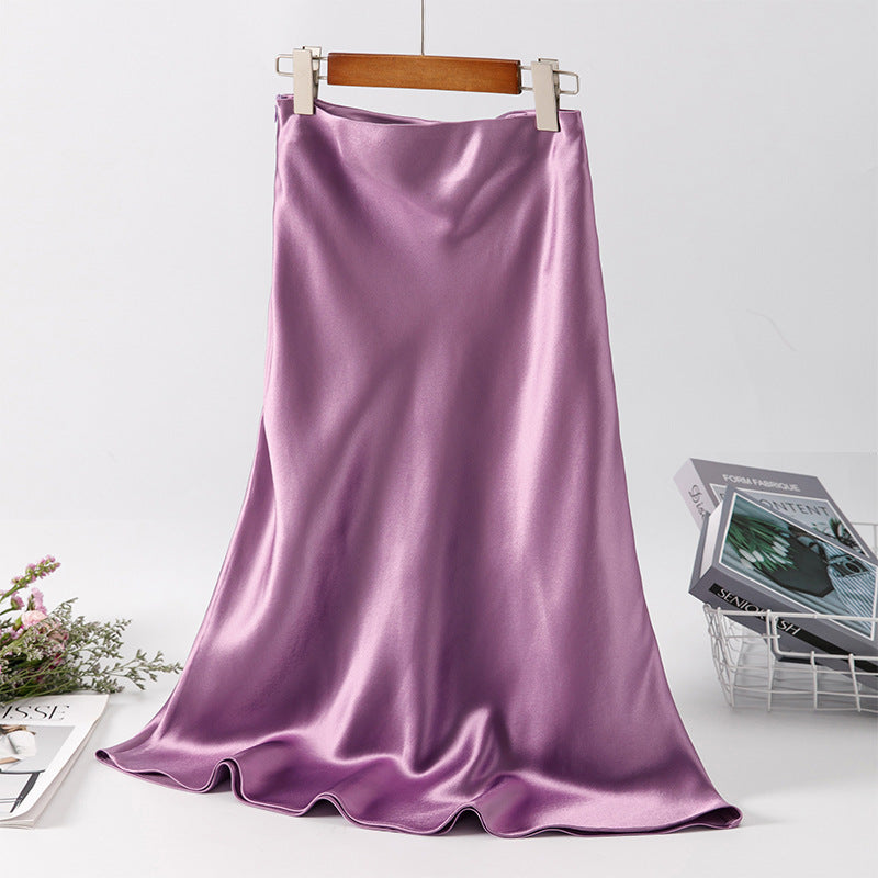 jupe longue satin violette élégante éléonore posée sur fond de livre, parfaite pour une tenue chic et raffinée