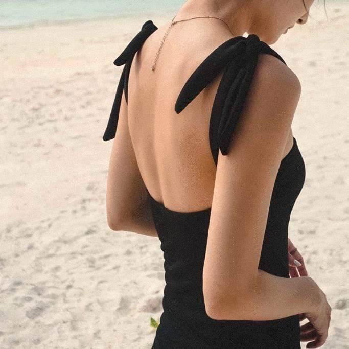 maillot de bain noir gainant adèle porté sur la plage avec vue arrière montrant les épaules dénudées et les nœuds