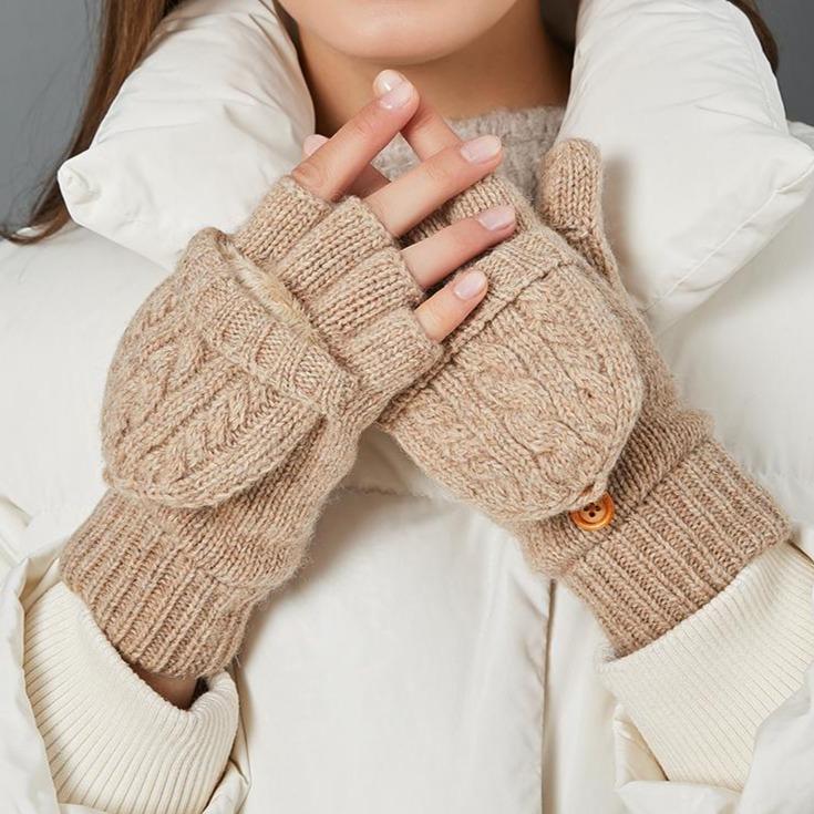 Moufles mitaines en laine beige pour femme avec un bouton en bois, portées avec une veste blanche pour l'hiver