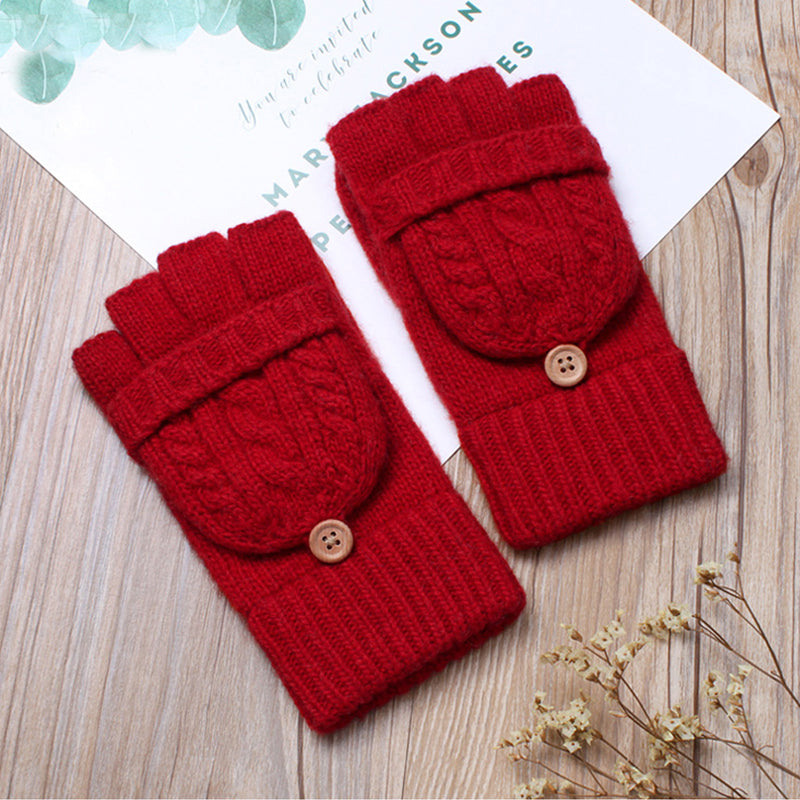 moufles mitaines laine rouge avec boutons en bois sur fond en bois avec quelques petites fleurs séchées et une carte