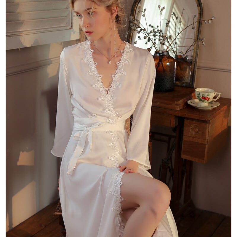 peignoir long en satin blanc pour femme mira avec dentelle élégante assise à côté d'une table en bois dans une chambre