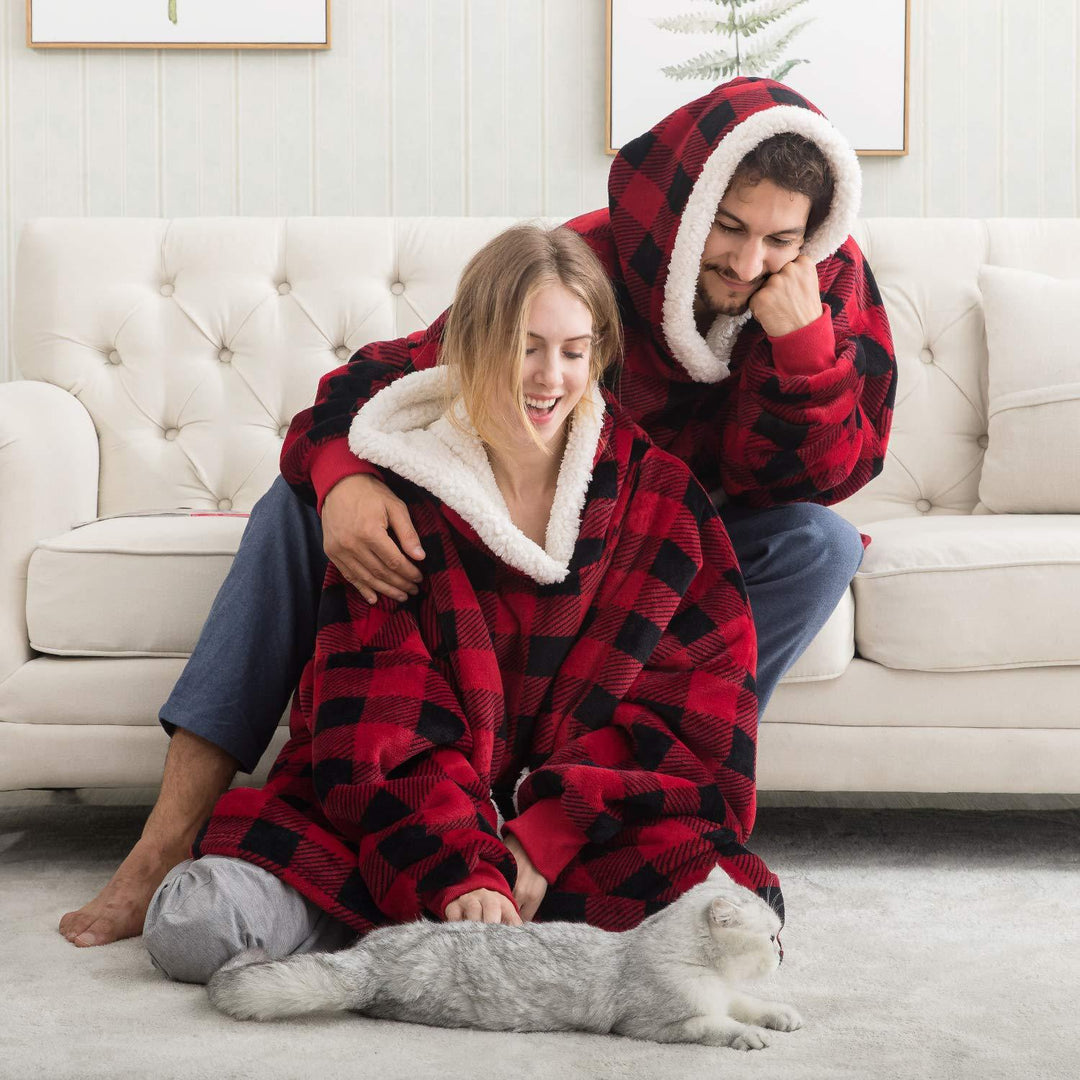 pull plaid couverture rouge et noir confortable, couple assis sur un canapé blanc avec un chat sur un tapis gris