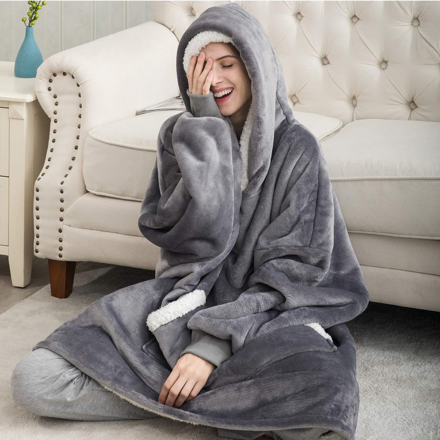 femme souriante portant un pull plaid couverture gris, assise confortablement sur le sol dans un salon élégant