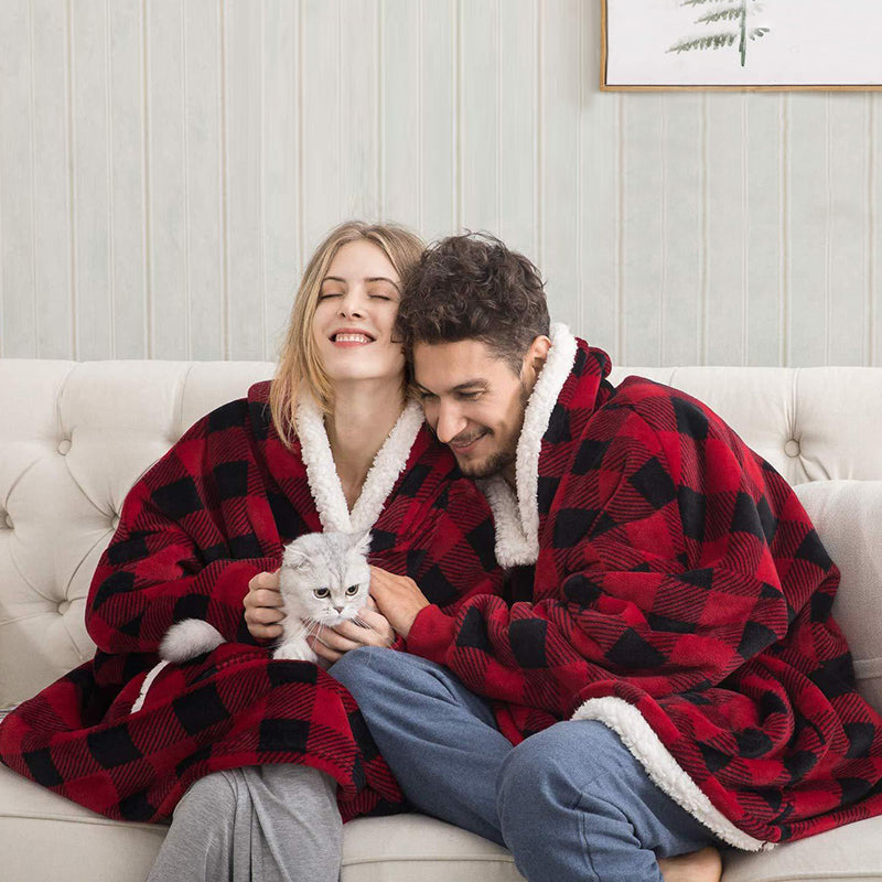 couple assis sur un canapé portant un pull plaid couverture rouge et noir avec un chat dans les bras