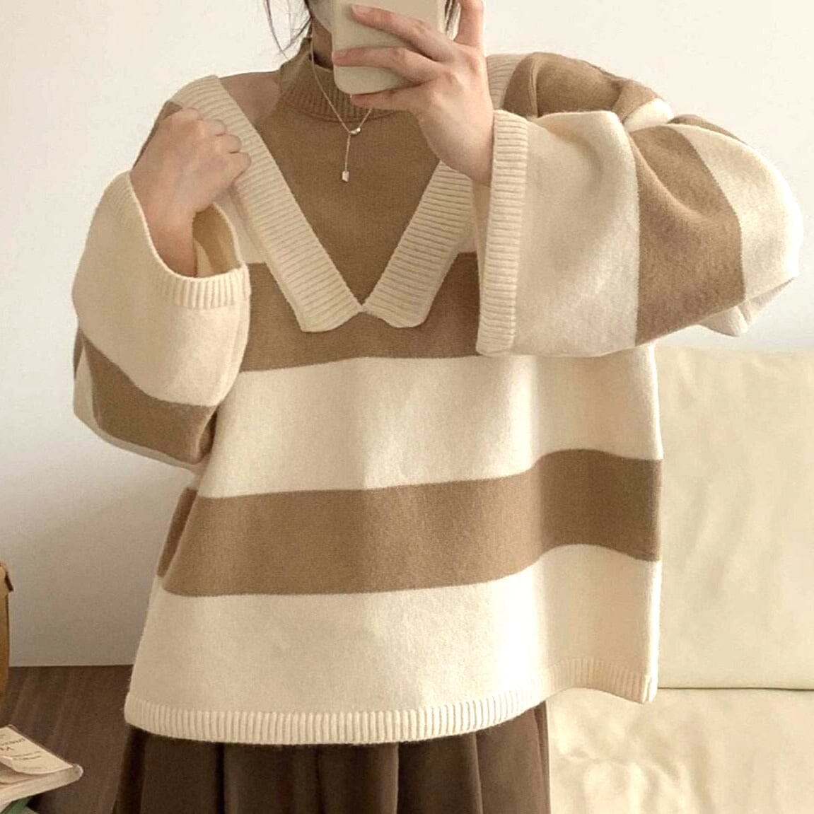 femme portant un pull à rayures beige et blanc, appelé nicole, en laine douce, avec manches longues et col en V