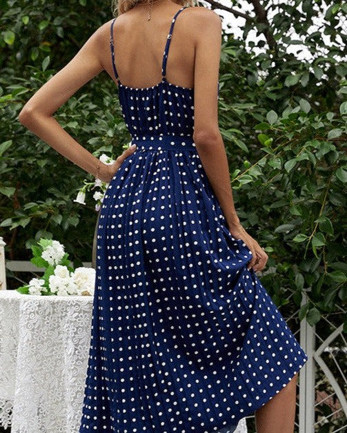 femme portant une robe mi longue à pois blanche et bleue, idéale pour les journées estivales et les occasions décontractées