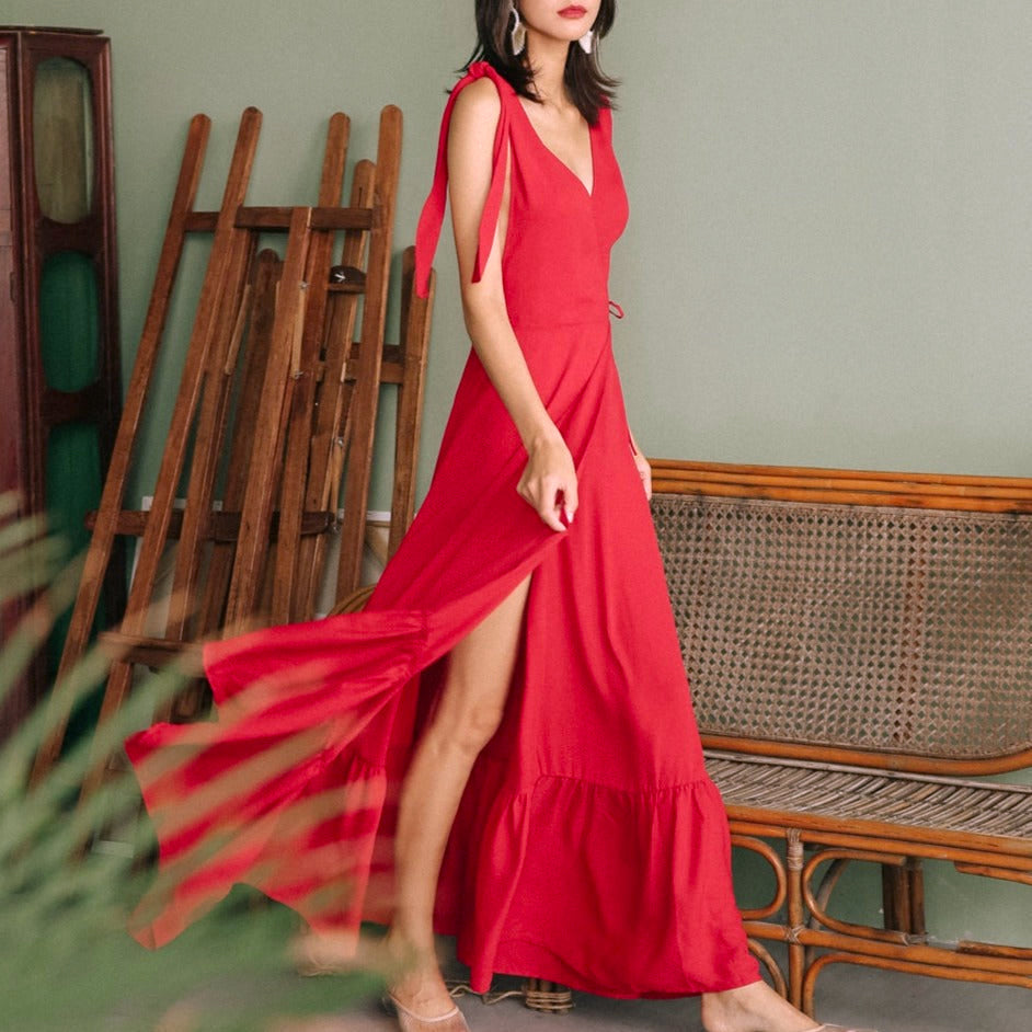 femme portant une robe longue rouge irina avec une fente devant, design élégant et moderne, fond intérieur avec chaise en osier