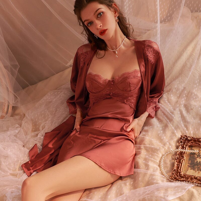 Robe nuisette en satin rose avec dentelle portée par un mannequin allongé sur un lit, style élégant et romantique