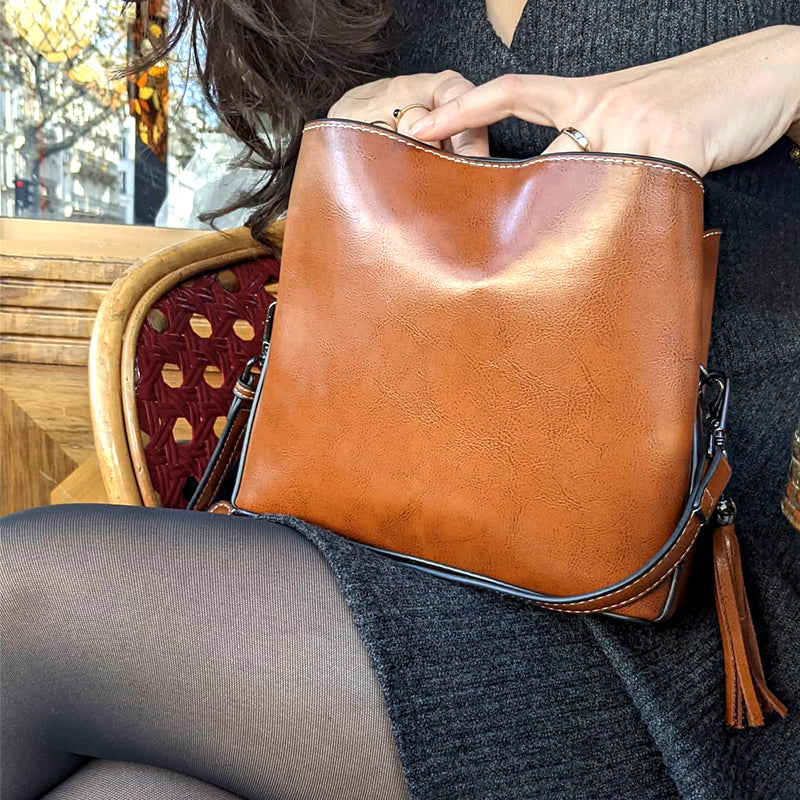 femme avec petit sac bandoulière cuir marron enzo, assise dans un café, parfait accessoire mode élégant et pratique