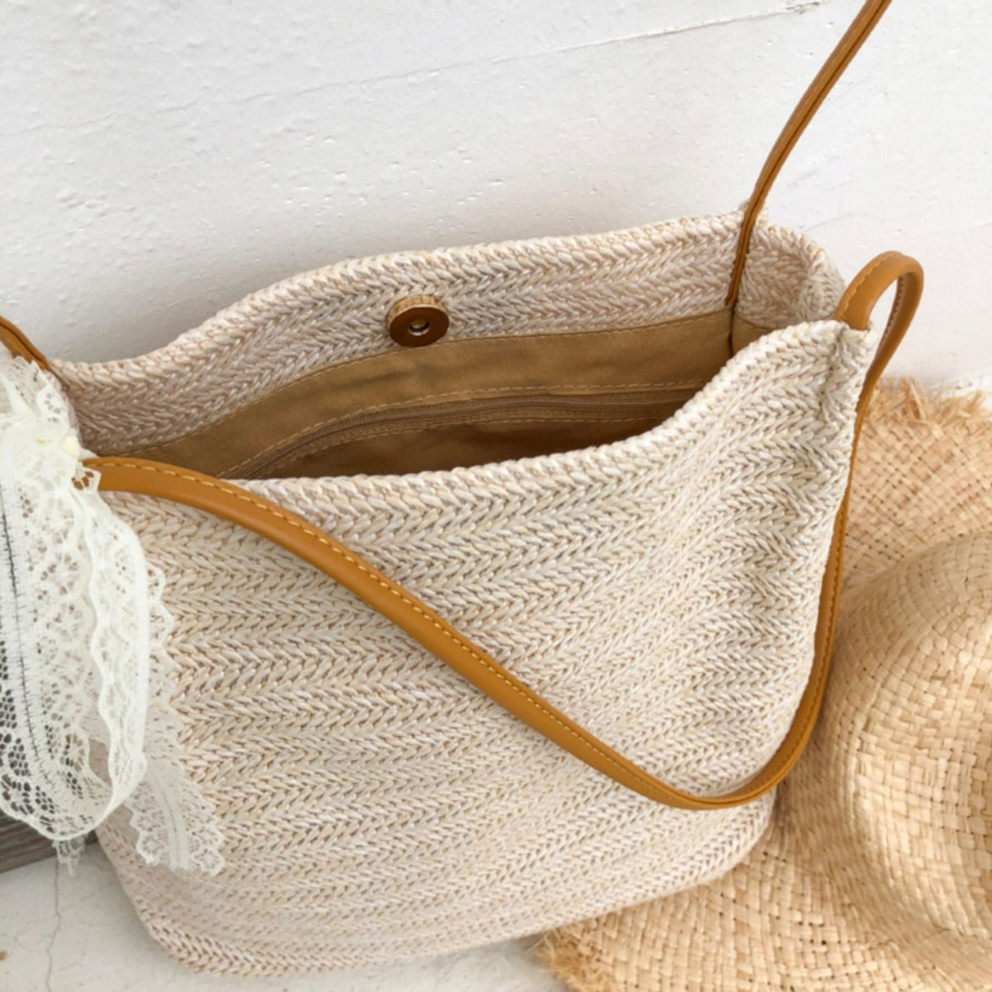 Cabas tressé en paille naturelle avec lanières en cuir marron, idéal pour les sorties estivales et les journées à la plage.