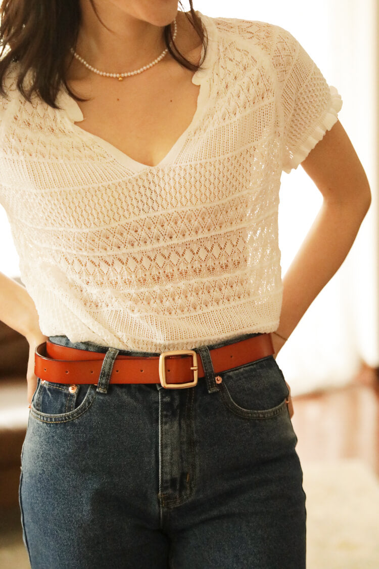 femme portant un top crochet blanc et un jean taille haute avec ceinture marron