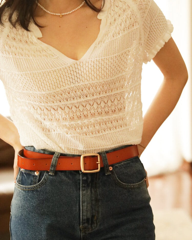 femme portant un top crochet blanc et un jean taille haute avec ceinture marron